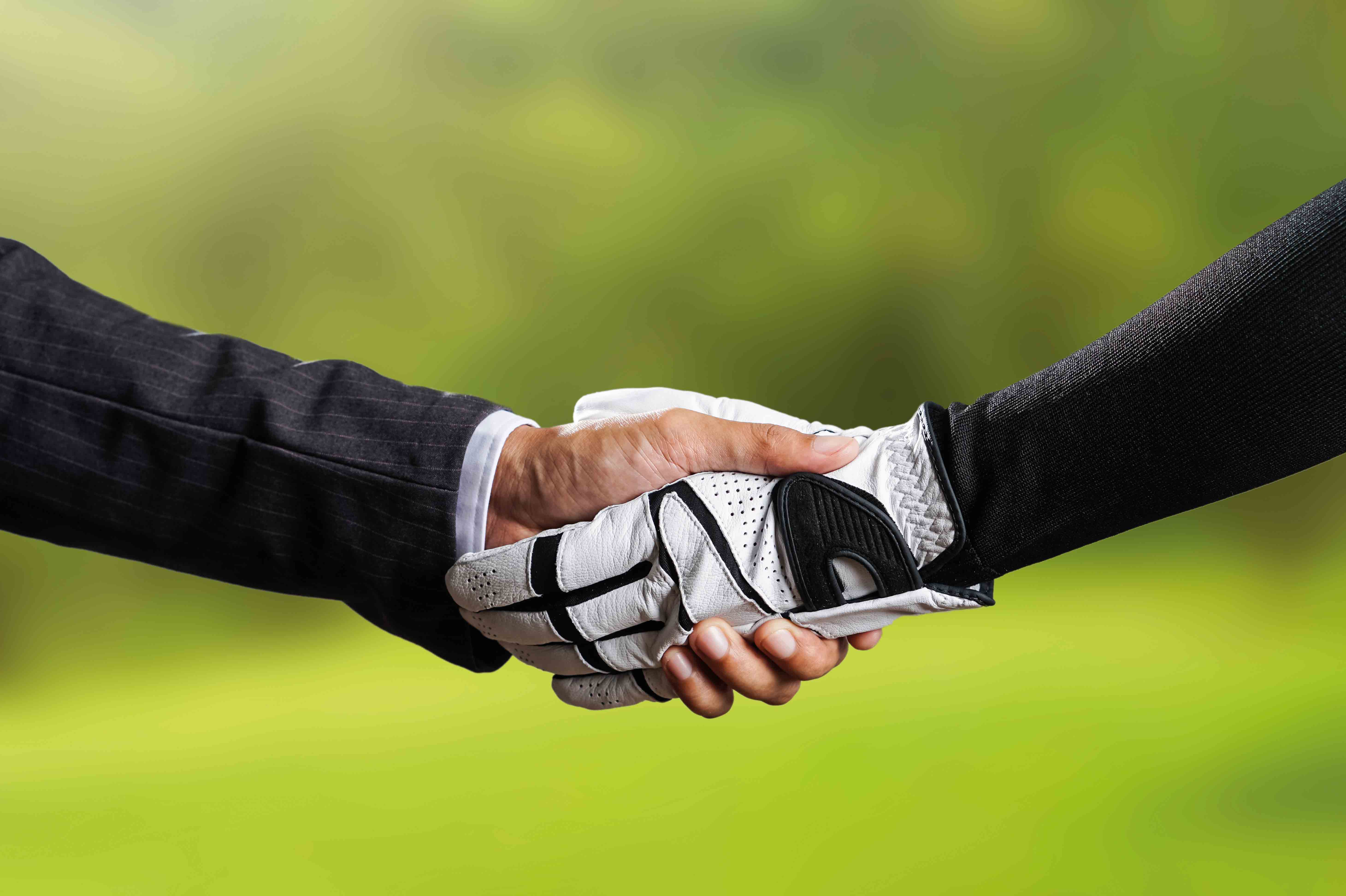 Man in suit shaking hands with golfer